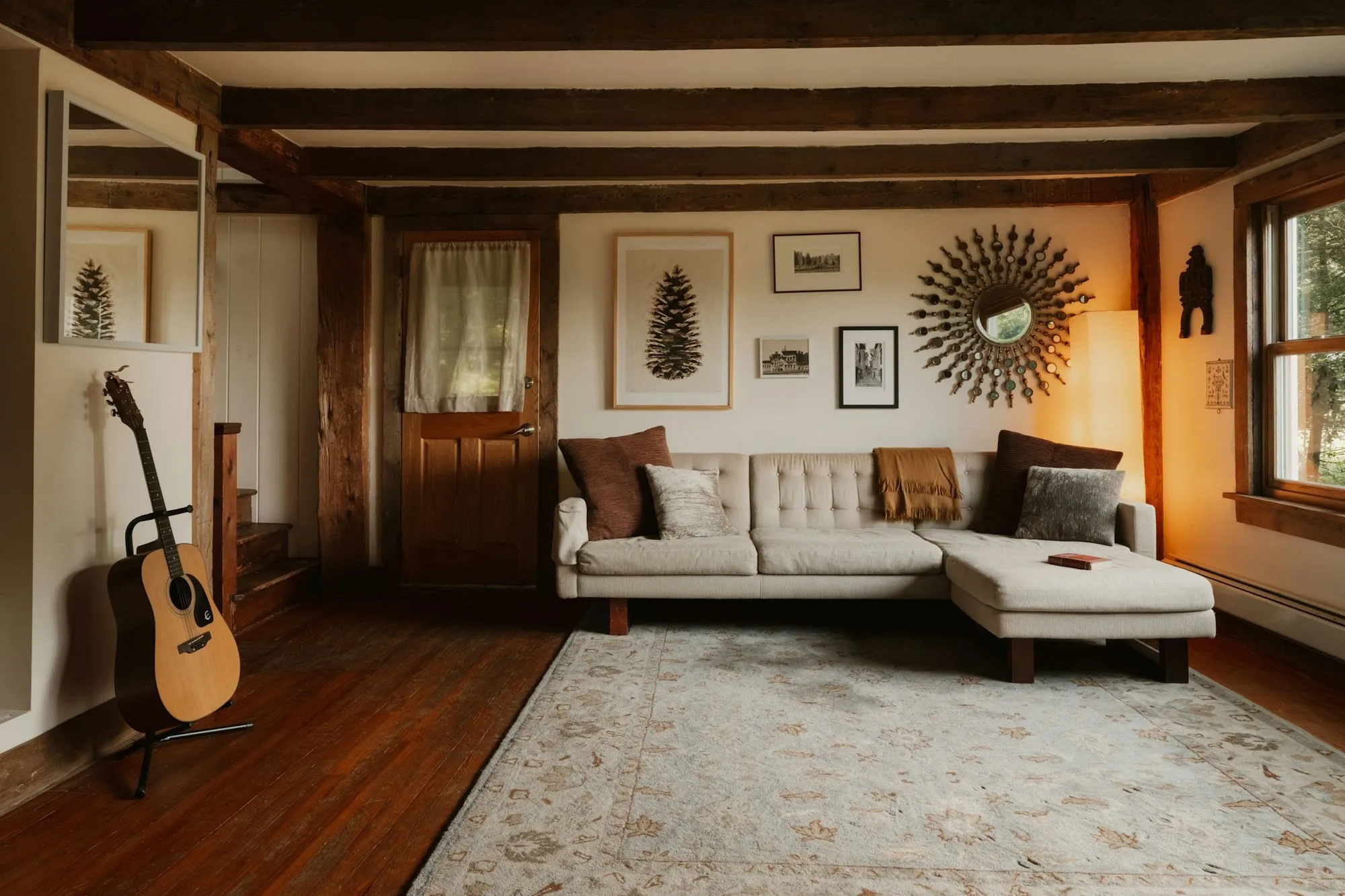 Family room with dark oak beams, wide plank floors and a cream sofa under framed prints