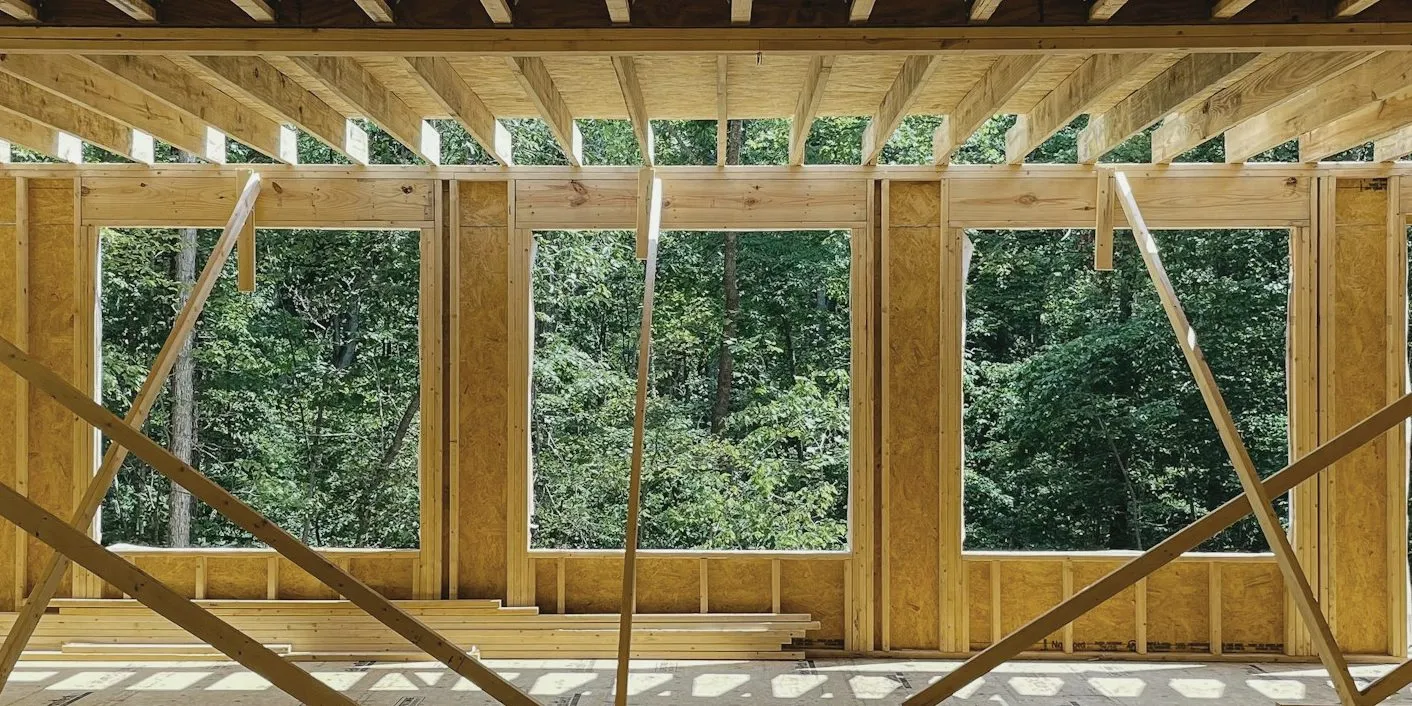 New addition framed in wood, with three window openings looking into green trees